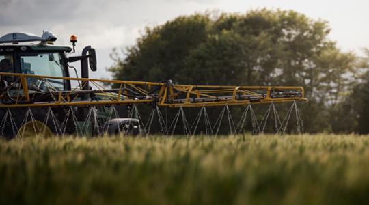 Tractor on a field spraying liquid fertiliser 